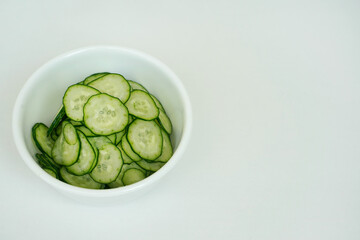 白い器に盛られた薄く輪切りにスライスされたキュウリ