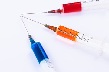 Medical Syringes with needles isolated on white. Macro shooting. Syringes filled with colored medication liquids.