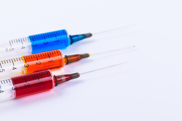 Medical Syringes with needles isolated on white. Macro shooting. Syringes filled with colored medication liquids.