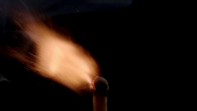 A mesmerizing close-up video captures the slow-motion ignition of a single matchstick against a stark black background, highlighting the intricate dance of flames and sparks.