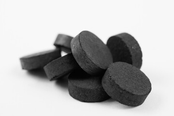 Activated charcoal tablets isolated on white. Macro shoot. Medical concept.