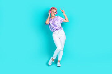 Full body photo of crazy girl striped t shirt hipster rock roll music lover mp3 headphones sign isolated on aquamarine color background