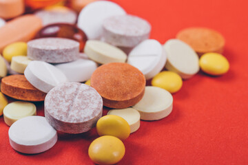 Tablets and pills on red background. Various treatments mixed. Variety of pills and medication. Close up. Macro. Medical concept.