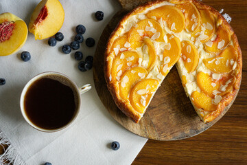 Homemade casserole with peaches on the wooden plate. Peaches, blueberries and coffee