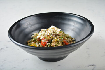 trio quinoa grain salad bowl with avocado, tomato, pea bean, carrot and brown rice in black bowl on white marble table background chef cook healthy poke bowl halal vegan food menu