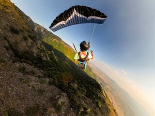 Fototapeta premium Extreme paraglider pilot flying over Bulgarian mountains, adventure concept.