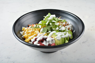 colourful healthy bowl assorted salad, vegetables, avocado, corn, bean, carrot rainbow salad dressing sauce on white marble table background chef cook healthy poke bowl halal vegan food menu