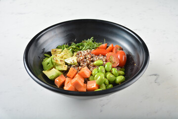 trio quinoa grain salad bowl with avocado, tomato, pea bean, carrot and brown rice in black bowl on white marble table background chef cook healthy poke bowl halal vegan food menu