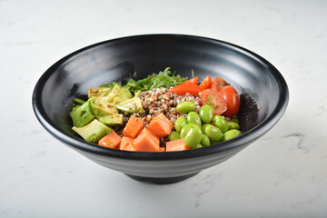 trio quinoa grain salad bowl with avocado, tomato, pea bean, carrot and brown rice in black bowl on white marble table background chef cook healthy poke bowl halal vegan food menu