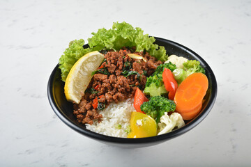 asian spicy thai basil minced pork rice bowl with fried vegetable salad in black bowl on white marble table background chef cook healthy poke bowl halal vegan food menu