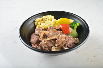 stir fried bbq bulgogi beef rice bowl with scrambled eggs and fried vegetable salad in black bowl on white marble table background chef cook healthy poke protein bowl halal vegan food menu