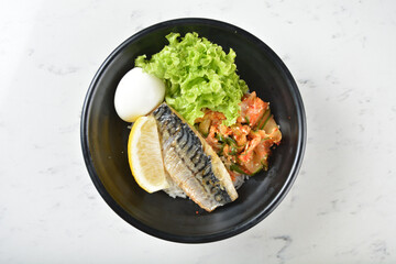bbq grill Korean Saba fresh fish seafood with lemon, boiled egg, kimchi and Japanese rice in black bowl on wood tray white marble table background chef cook healthy poke bowl halal protein food menu