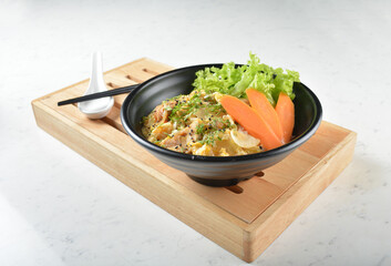 japanese oyakodon chicken fried egg white rice with carrot vegetable salad in black bowl on wood...