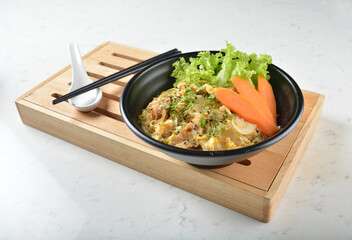 japanese oyakodon chicken fried egg white rice with carrot vegetable salad in black bowl on wood tray white marble table background chef cook healthy poke bowl halal vegan food menu