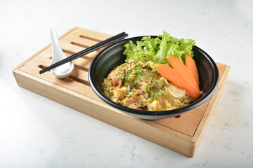 japanese oyakodon chicken fried egg white rice with carrot vegetable salad in black bowl on wood tray white marble table background chef cook healthy poke bowl halal vegan food menu