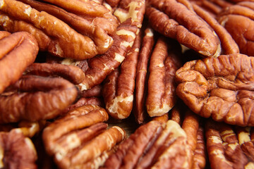 Pecan nuts kernel texture background closeup. Heap of peeled pecan halves. The background showcases pecans rustic charm