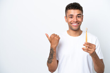 Young Brazilian man brushing teeth isolated on white background pointing to the side to present a...
