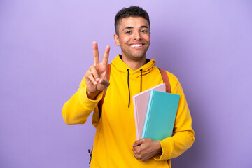 Young student Brazilian man isolated on purple background smiling and showing victory sign