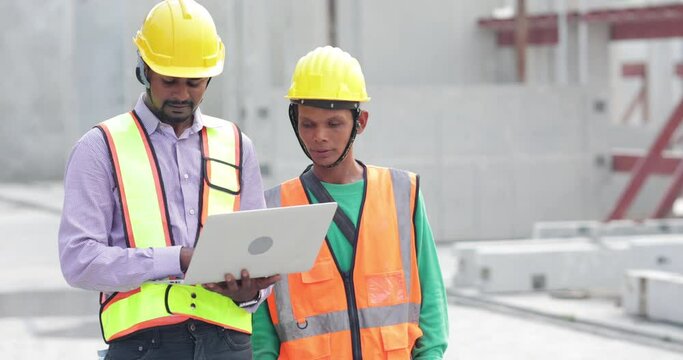 Asian indian construction architect Engineering man and senior worker in safety hardhat working on laptop computer at Prefabricated concrete factory Heavy industrial