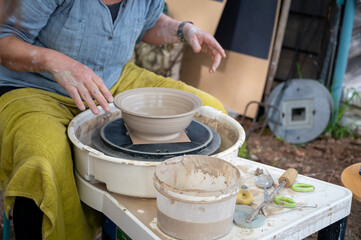 Making of mud pot on potters wheel during workshop outdoor