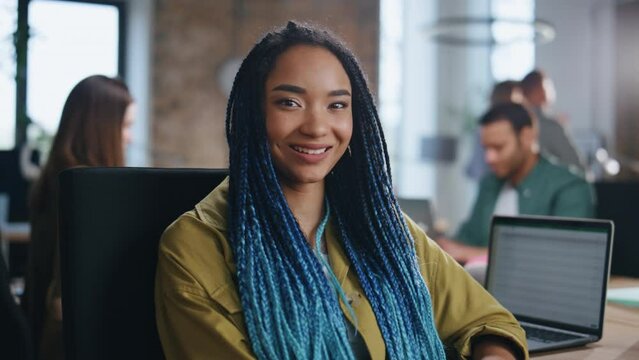Trendy girl manager posing in office with working team at backdrop close up.