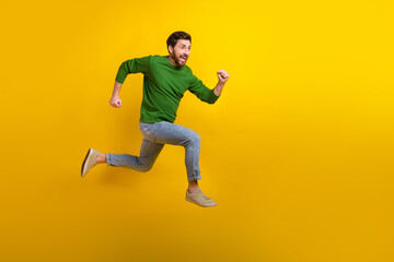 Full body photo of running determined young man brunet wear casual outfit jumping motivation do more isolated on yellow color background