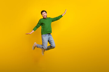 Obraz na płótnie Canvas Full size cadre of crazy flying jumping shopaholic guy wearing denim jeans stylish outfit wings arms isolated on yellow color background