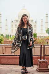 Attractive east asian woman in black dress stay on Taj Mahal background, beautiful young girl tourist walking in Agra city, India, east asian female covered with black scarf portrait in Taj Mahal