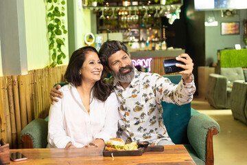 Indian couple using smartphone at restaurant