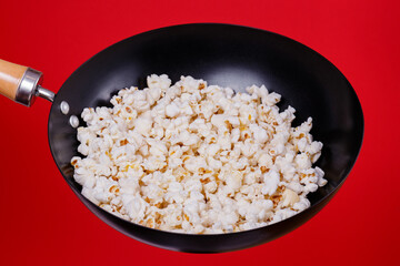 Popcorn in the frying pan on a red background.