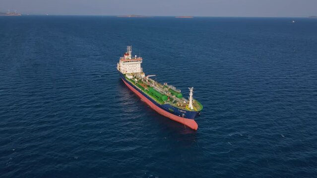 Chemical tanker ship on anchorage in calm blue water, aerial wide shot
