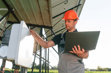 Standing and holding laptop. Man is doing operating and maintenance in solar power plant
