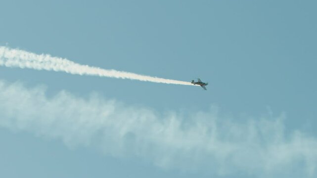 Aerobatics with Stunt plane and white smoke trail