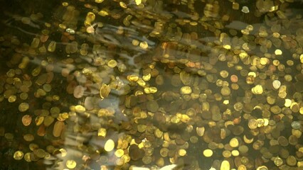 Treasures at the bottom of the ocean. Gold coins underwater. Lots of coins in the fountain. Waves and swaying movement of water. Coin money.