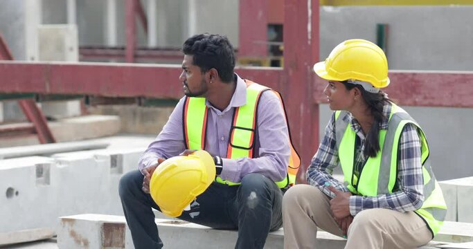 Happy worker enjoying free time. Asian indian man and woman warehouse worker sitting on workshop site break relax time at precast factory.