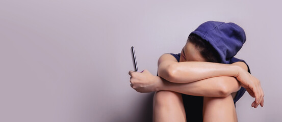 Social Media affect a Physical and Mental Health Concept. a Stress, Anxiety, Depression Women sitting by the Wall and Looking at her Mobile Phone. Social Bullying, Social Addict, Waiting for Message