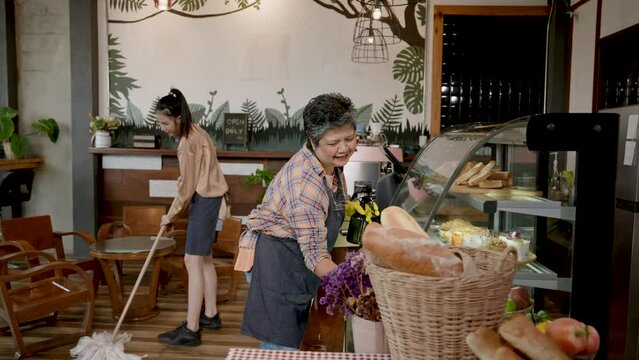Asian beautiful barista Helping an elderly single mother cafe shop cleaning Prepare to close the shop in the evening. After all the customers have returned Getting ready for opening tomorrow