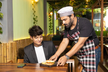 Waiter serving food to customer at restaurant