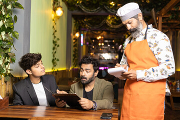 Indian man ordering food to waiter at restaurant