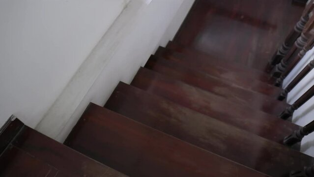 Slow-motion footage of walking down the old wooden stairs inside the house.
