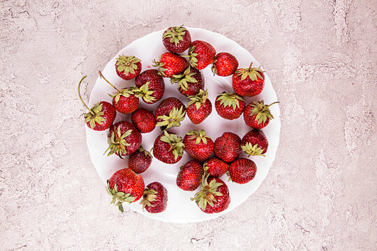 Frech ripe strawberries 0n white blate over on gray concrete background.