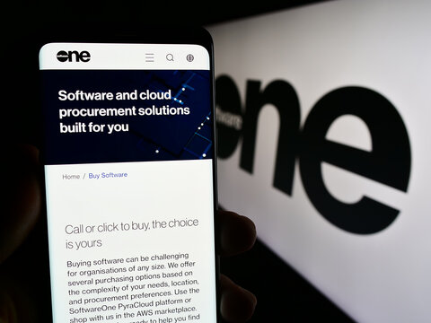 Stuttgart, Germany - 08-05-2023: Person holding mobile phone with web page of Swiss software company SoftwareOne AG on screen in front of logo. Focus on center of phone display.