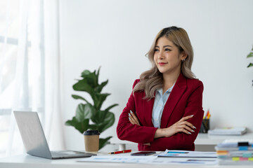 Cheerful and confident Asian businesswoman While sitting cross arms at the desk Paperwork in preparation for a meeting at modern workplace.