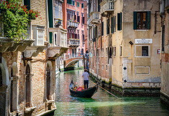 Fototapeta na wymiar Traditional gondola ride on the narrow water canals.Tourists in Venice.