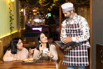 Waiter giving bills or invoice to females customer after lunch or dinner
