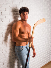 Handsome young man shirtless with hockey stick in hands - 633739198