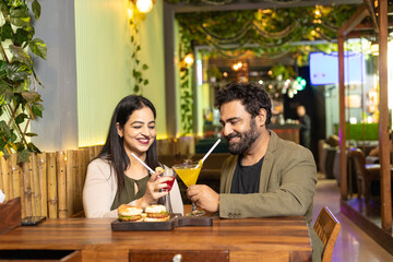 Indian Couple enjoying food and drink at restaurant