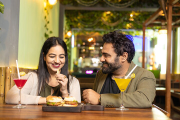 Indian Couple enjoying food and drink at restaurant
