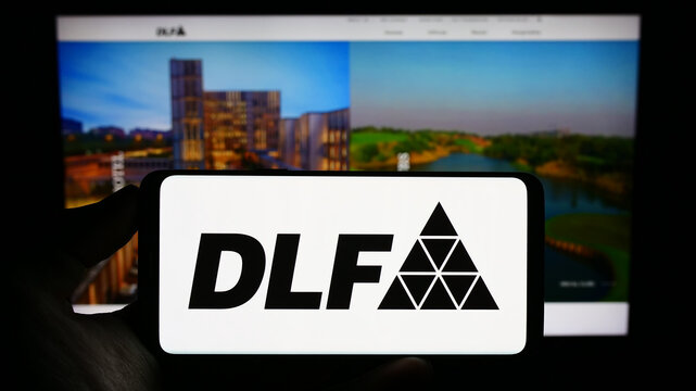 Stuttgart, Germany - 08-06-2023: Person holding cellphone with logo of Indian real estate company DLF Limited on screen in front of business webpage. Focus on phone display.