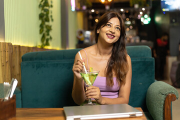 Indian Corporate woman taking cold drink and giving happy expression at restaurant.